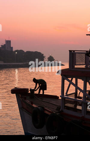 L'Inde, Mumbai, Maharashtra, district de Colaba, l'homme se découpant sur le bateau à Mumbai port près de porte de l'Inde Banque D'Images