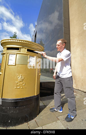 L'homme en utilisant golden royal mail post box à Leeds célébrant nicola adams boxing gagnante d'or aux Jeux olympiques de 2012 à Londres Uk Banque D'Images