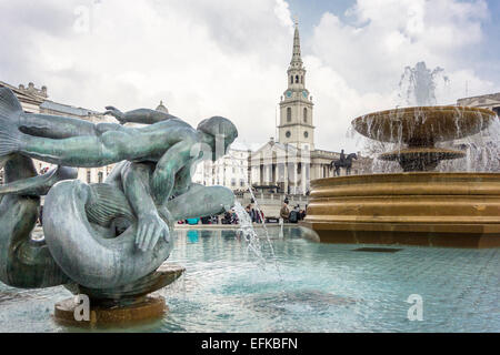 Statue d'une sirène avec les dauphins dans les fontaines de Trafalgar Square, avec une statue du roi George IV sur son cheval et St Mart Banque D'Images