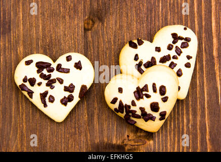 Les cookies en forme de coeur avec le chocolat sur vu de dessus de table en bois Banque D'Images