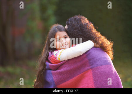 Mère et fille enveloppée de blanket in garden Banque D'Images