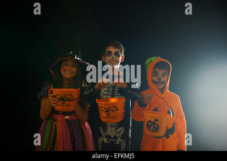 Portrait de frères et sœur portant des costumes de halloween holding trick ou traiter des seaux Banque D'Images