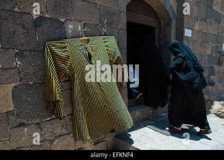 Deux femmes non identifiées, vêtues de noir et un enfant entrer dans un bâtiment en pierre le 5 mai 2007, à Kawkaban, Yémen. Banque D'Images