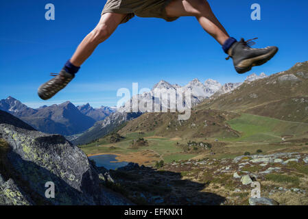 Les jambes de male hiker sautant au dessus des rochers, Lai da Fons, Canton des Grisons, Suisse Banque D'Images