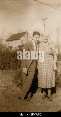 Le Canada. Dec 12, 2014. CIRCA 1950 : Reproduction d'une photo montre un jeune homme en costume d'affaires posant avec une femme âgée sur un arrière-plan de maison à étage privé © Igor Golovniov/ZUMA/ZUMAPRESS.com/Alamy fil Live News Banque D'Images