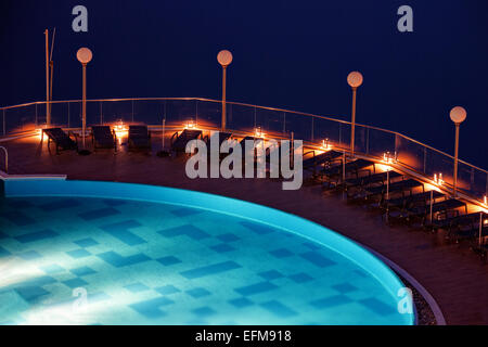 Des chaises longues au bord de la piscine dans une scène de nuit. Banque D'Images