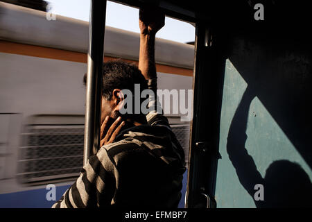 Un homme travaille sur un train de banlieue de Mumbai, Inde Banque D'Images