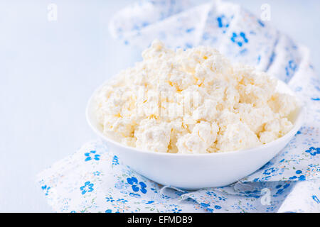 Bol de fromage cottage en blanc sur fond bleu clair, selective focus Banque D'Images