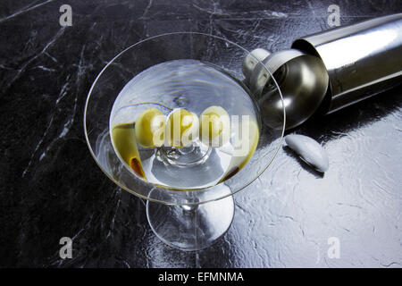 Olive trois martini en verre a pied avec shaker et Ice Cube sur ardoise noire Banque D'Images