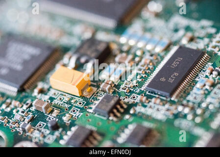 Circuits imprimés informatiques en gros plan | WASHINGTON — Des puces montées en surface et un condensateur au tantale encombrent une carte imprimée verte dans ce détail macro, illustrant la densité du matériel informatique moderne. Des codes de référence sérigraphiés à côté de chaque composant, tels que U50 et C503, guident les techniciens lors de l'assemblage et des tests de diagnostic. Les traces en cuivre stratifiées de la carte transportent les signaux électriques entre les composants semi-conducteurs à grande vitesse. Banque D'Images