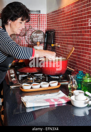 Femme en remuant un pot rouge sur la cuisinière pendant un cours de cuisine, quartier Bellavista, Santiago, Chili, Amérique du Sud Banque D'Images