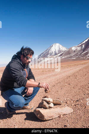 Homme portant lunettes glacier chilien stacks rochers pour créer un apacheta devant le volcan Licancabur, San Pedro de Atacama Dese Banque D'Images