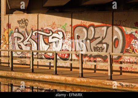 Le Graffiti sous un pont routier, reflétée dans les eaux gelées de la Canal de Lancaster, Preston, Lancashire Banque D'Images