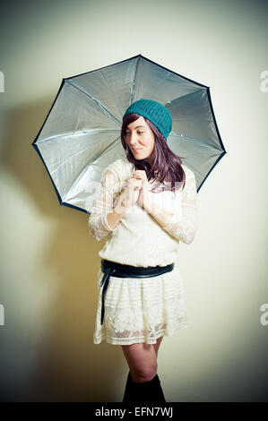 Jeune femme en 70s style hippie posing looking down avec parapluie vintage effet de couleur Banque D'Images