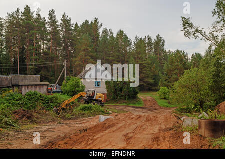 La construction de routes.Le constructeur sur l'excavatrice creuse le sable pour le pont - un tuyau à travers un flux. Banque D'Images