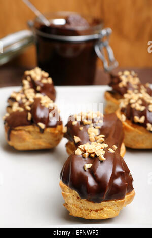 Éclairs au chocolat et des écrous sur la plaque sur fond de bois Banque D'Images