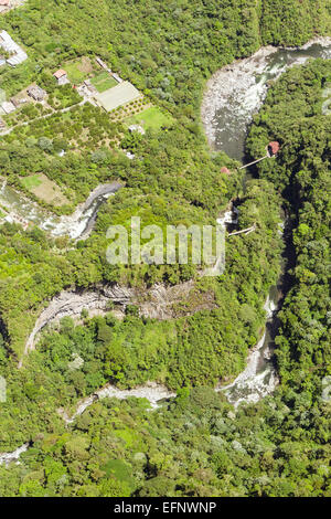 Une perspective aérienne montre une rivière sinueuse traversant une vallée dense et verdoyante. La rivière coule sur des lits rocheux et crée de petits rapides, entourés d'une végétation épaisse et de pentes boisées. Sur le Banque D'Images