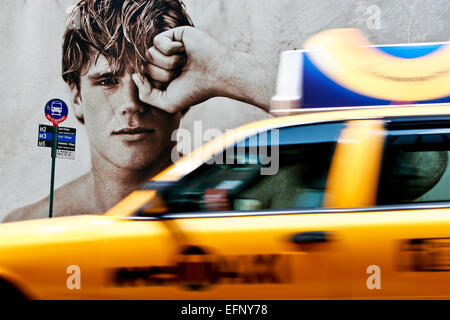 Beau jeune modèle masculin sur la mode des panneaux d'affichage à l'arrêt de bus, taxi taxi jaune de flou en passant. La 5e Avenue, Manhattan, New York City, NY Banque D'Images