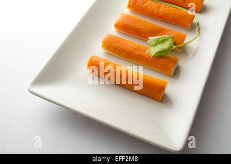 Bâtonnets de surimi ou de crabe dans une plaque rectangulaire blanche. . Fond blanc Banque D'Images