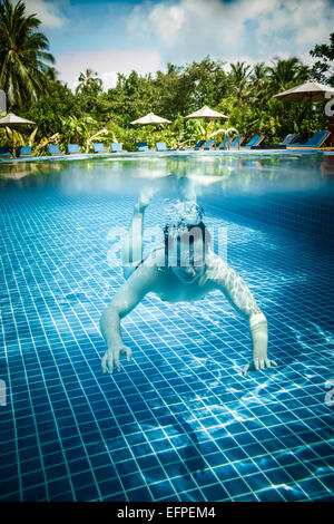 L'homme plonge dans une piscine donne sur l'eau et sous l'eau. Les Maldives. Banque D'Images