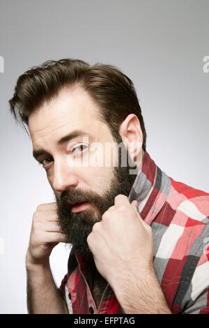 Portrait de jeune homme barbu posant holding up shirt collar Banque D'Images