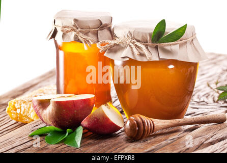 Les canettes en verre plein de miel et de pomme sur l'ancienne table en bois. Banque D'Images