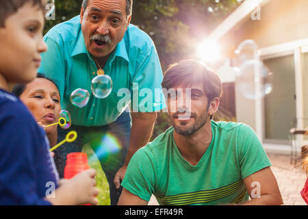 Family blowing bubbles in garden Banque D'Images