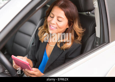 Business Woman using smartphone in car Banque D'Images