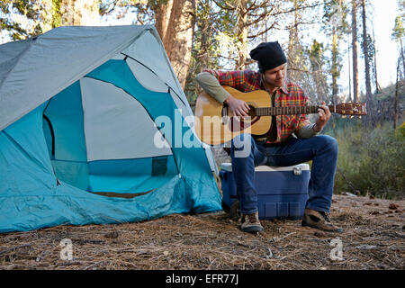 Jeune homme jouant de la guitare en camping-forêt, Los Angeles, Californie, USA Banque D'Images