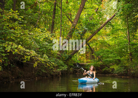 Jeune femme du kayak sur la rivière en forêt, Cary, Caroline du Nord, États-Unis Banque D'Images