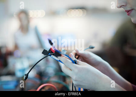 Une jeune femme à l'aide des câbles de connexion usb et conduit dans un atelier de réparation d'ordinateur. Banque D'Images