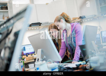 Atelier de réparation d'ordinateur. Deux femmes travaillant ensemble se penchant ou un compteur. Banque D'Images