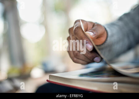 Close up de la main d'un homme de feuilleter les pages d'un livre. Banque D'Images