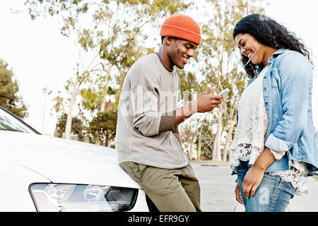 Jeune couple en partage parking musique smartphone Banque D'Images