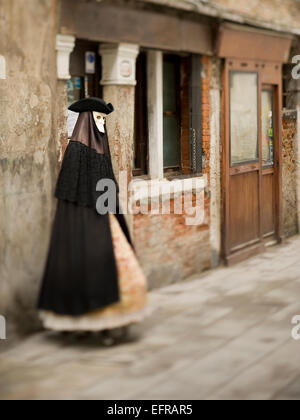 Une personne en costume de carnaval, masque chapeau et manteau à Venise debout sur la rue Banque D'Images