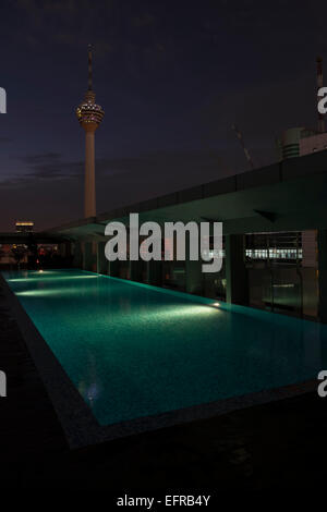 La KL Tower vu depuis le toit d'un bâtiment situé à proximité de Kuala Lumpur, Malaisie, la nuit. Piscine en premier plan. Banque D'Images