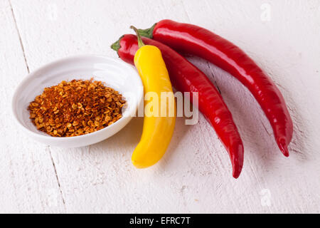 Fresh red Chili Peppers et jaune avec un petit bol de poivre de Cayenne séché utilisé comme épice chaude et la saveur piquante assaisonnement Banque D'Images