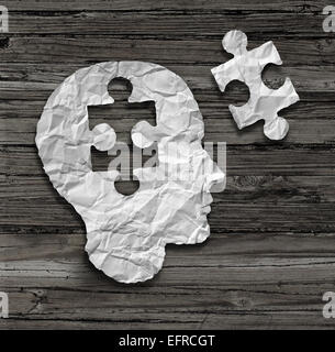 Cerveau tête Puzzle concept comme un visage humain profil réalisés à partir de papier blanc froissé avec un jigsaw piece découper sur un fond sombre rustique comme un symbole de la santé mentale. Banque D'Images