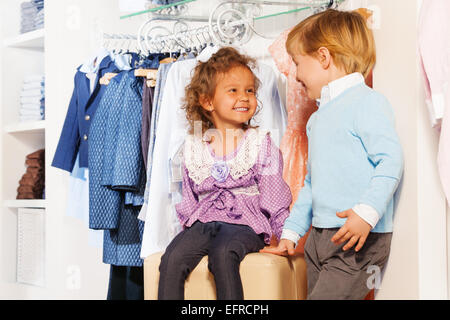 Smiling cute boy regarde tout en faisant du shopping de fille Banque D'Images