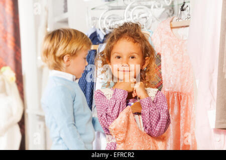 Fille avec robe et garçon derrière choisissant des vêtements Banque D'Images