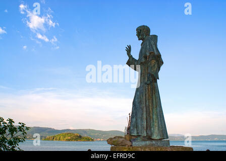 Statue de Saint François d'Assise, l'Isola Maggiore (à l'arrière-plan Isola Minore), le lac Trasimène, Ombrie, Italie Banque D'Images