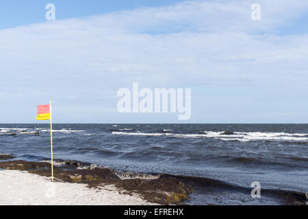 La plage rouge et jaune d'un drapeau flottant au vent sur une plage au Danemark Banque D'Images