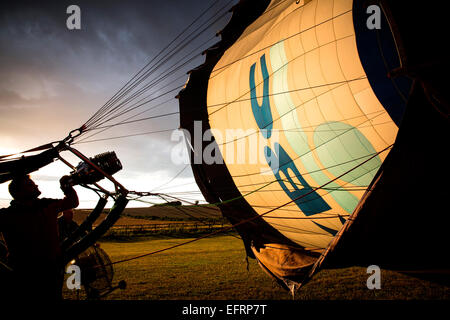 L'homme du gonflage ballon à air chaud au coucher du soleil, l'Oxfordshire, Angleterre Banque D'Images