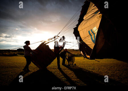 Le gonflage de l'équipage d'accueil hot air balloon at sunset, south Oxfordshire, Angleterre Banque D'Images