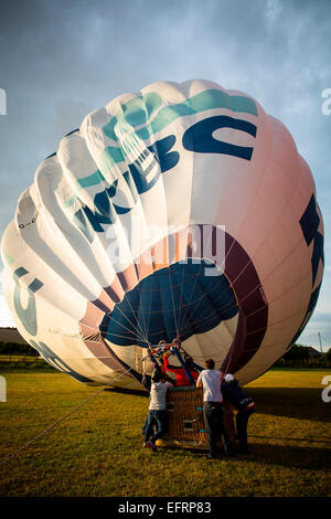 Le gonflage de l'équipage d'accueil hot air balloon at sunset, south Oxfordshire, Angleterre Banque D'Images