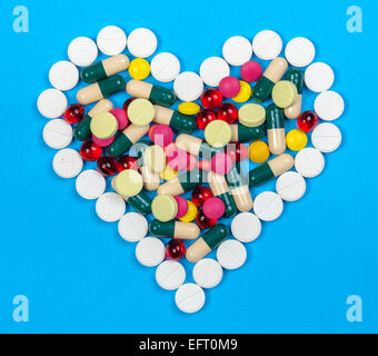 Pilules colorées en forme de coeur sur fond bleu Banque D'Images
