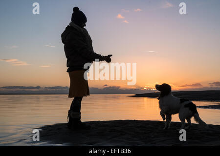 Silhouette d'une femme dog walker au coucher du soleil à Aberdovey / Aberdyfi village sur la rivière Dyfi journée ensoleillée,Mid Wales Gwynedd, Pays de Galles, Banque D'Images