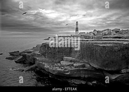 Portland Bill phare contre un ciel lumineux avec des blocs de Pierres de Portland et falaises en premier plan, vue sud-ouest comme une image en noir et blanc Banque D'Images