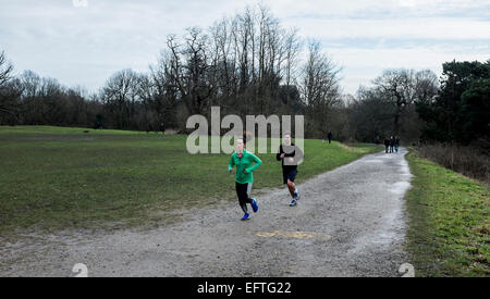 Porteur du jogging jusqu'à une colline sur Hampstead Heath sur un samedi matin d'hiver Banque D'Images