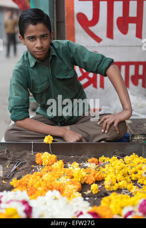 Jodhpur, Rajasthan, Inde. Teenage boy vente de guirlandes de fleurs d'un décrochage dans le bazar Banque D'Images